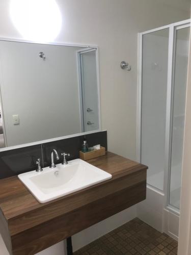 uma casa de banho com um lavatório branco e um espelho. em Cooks Endeavour Motor Inn em Tweed Heads