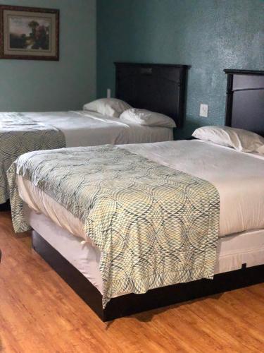 two beds in a room with wooden floors at Calimesa Inn in Calimesa