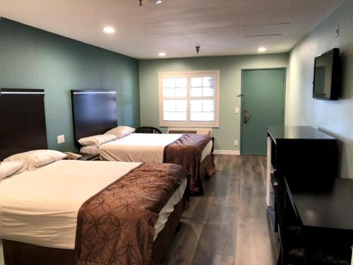 Habitación de hotel con 2 camas y TV en Calimesa Inn, en Calimesa