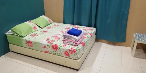 uma pequena cama com flores num quarto em Hazim Homestay Changlun Pakej Esklusif em Changlun