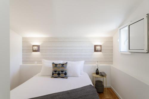 een witte slaapkamer met een bed en een raam bij Vila Madre Deus I in Lissabon