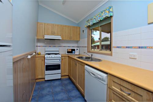 a kitchen with wooden cabinets and a sink at Koonwarra Holiday Park in Lakes Entrance