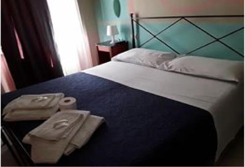 una camera da letto con un grande letto con due asciugamani di HOTEL MAIDA a Follonica