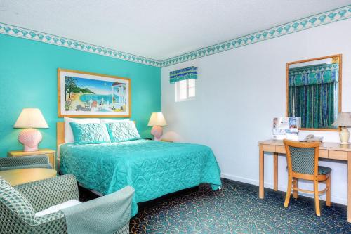 a bedroom with a bed and a desk and a chair at Morro Bay Sandpiper Inn in Morro Bay