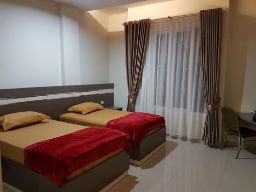 um quarto com 2 camas, uma secretária e uma janela em Hotel Grand Sigma em Lahat