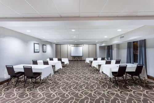 a conference room with white tables and chairs and a screen at Wingate by Wyndham High Point Greensboro in High Point