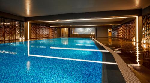 een groot zwembad met blauw water in een gebouw bij RIHGA Royal Hotel Kyoto in Kyoto