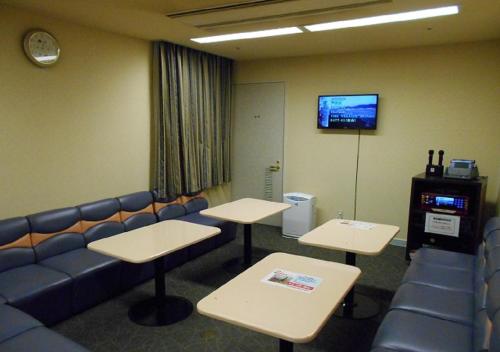 a waiting room with tables and a couch and a tv at Hotel New Momiji in Nasushiobara