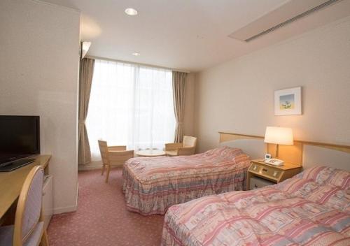 a hotel room with two beds and a television at Hotel New Momiji in Nasushiobara