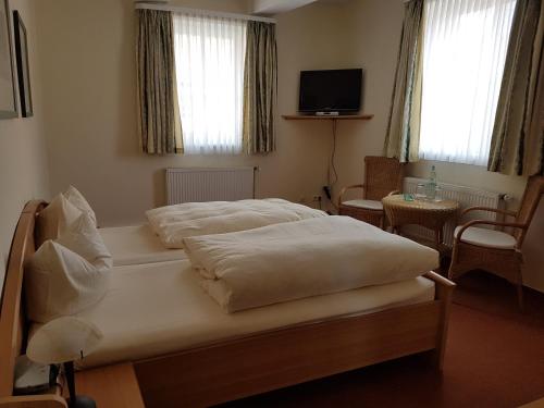 a bedroom with two beds and a tv and windows at Ratskeller Nörten in Nörten-Hardenberg