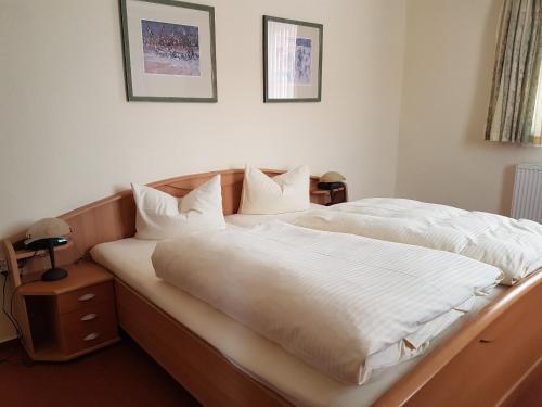 a bedroom with a large bed with white sheets and pillows at Ratskeller Nörten in Nörten-Hardenberg