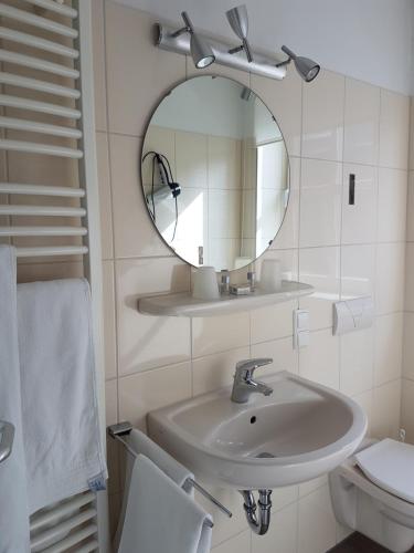 a white bathroom with a sink and a mirror at Ratskeller Nörten in Nörten-Hardenberg