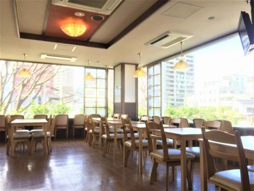 uma sala de jantar com mesas, cadeiras e janelas em Hotel Matsumoto Yorozuya em Matsumoto