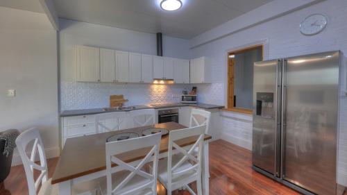 a kitchen with white cabinets and a stainless steel refrigerator at Endeavour Court Motor Inn in Dubbo