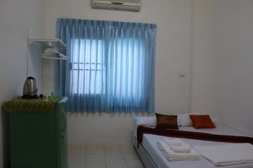 a bedroom with a bed and a window with blue curtains at J Home apartment Hadyai in Hat Yai