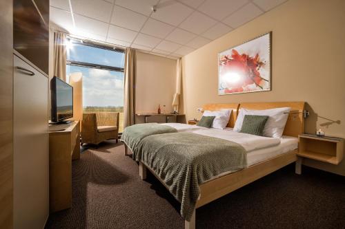 ein Hotelzimmer mit einem Bett und einem TV in der Unterkunft Hotel der Freiraum in Güssing