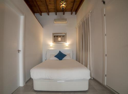 a bedroom with a white bed with a blue pillow at Triana Boho Chic WiFi in Seville