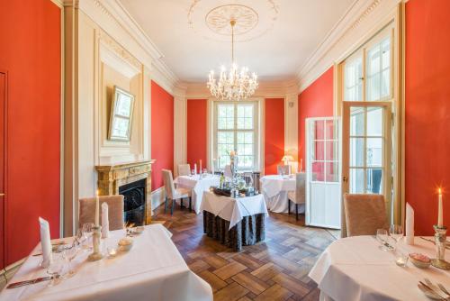 a dining room with red walls and tables and a chandelier at Schloss Kartzow in Potsdam