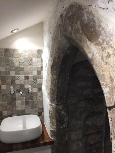 a bathroom with a stone wall and a white toilet at Little Arch in Tenby