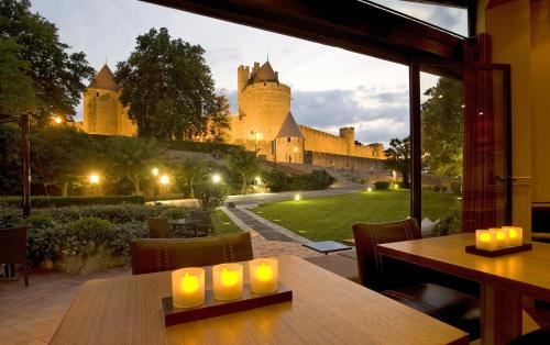 a dining room with a view of a castle at Hôtel du Château & Spa - Teritoria in Carcassonne