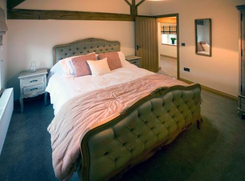 a bedroom with a large bed with pillows on it at Honeysuckle Cottage, Drift House Holiday Cottages in Astbury