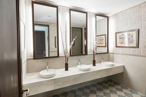 a bathroom with three sinks and three mirrors at Amanuba Hotel & Resort Rancamaya in Bogor