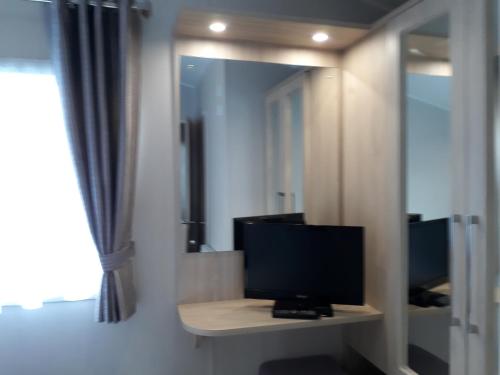 a television sitting on a table in front of a mirror at Aspen Retreat, Haggerston Castle in Cheswick