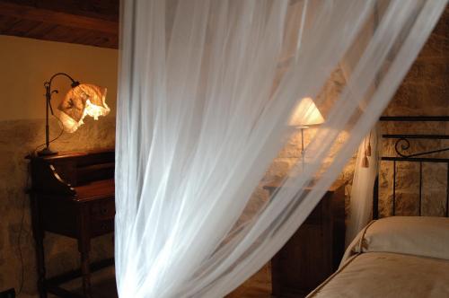 a bedroom with a bed with white curtains and a lamp at Agriturismo Il Granaio Hotel & SPA in Modica