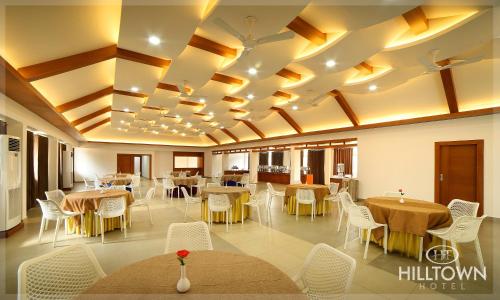 a dining room with tables and white chairs at Kgees - Hill Town Hotel in Kattappana