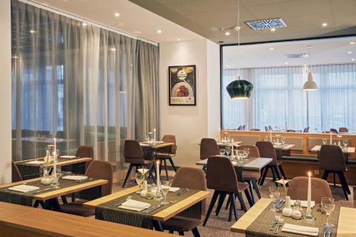 a restaurant with tables and chairs and windows at H4 Hotel Leipzig in Leipzig