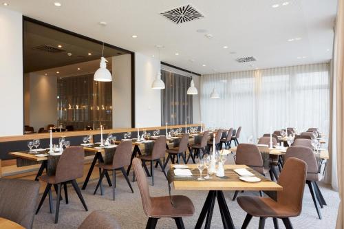 a dining room with wooden tables and chairs at H4 Hotel Leipzig in Leipzig