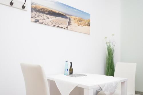a white dining room with a table and a picture of a beach at Miniapartment am Dalberg in Aschaffenburg