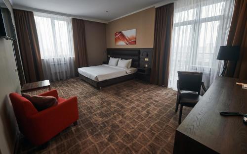 a hotel room with a bed and a chair at Ramada by Wyndham Rostov-on-Don Hotel and Spa in Rostov on Don