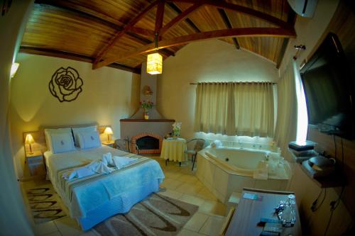 a bedroom with a bed and a bath tub at Pousada Villa Da Montanha in São Bento do Sapucaí