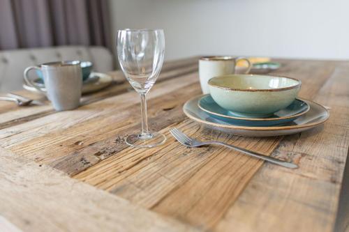 a wooden table with a wine glass and a bowl at HOMEBOUND APARTMENTS Salzburg City II - contactless check-in in Salzburg