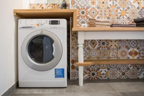 a washing machine in a bathroom next to a shelf at HOMEBOUND APARTMENTS Salzburg City II - contactless check-in in Salzburg