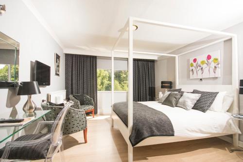 a white bedroom with a bed and a desk at The Manor Hotel in Crickhowell