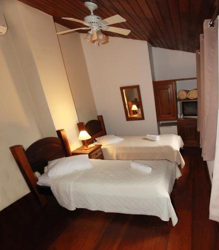 a room with two beds and a ceiling fan at Pousada do Cais in Paraty