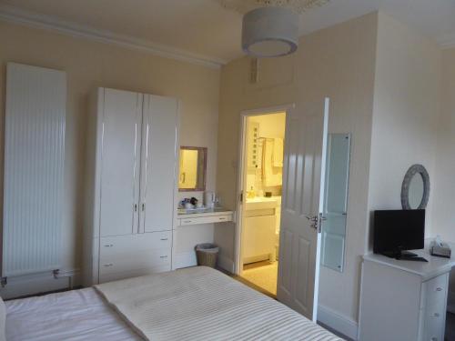 a bedroom with a bed and a television in it at Woodlands Guest House in Saundersfoot