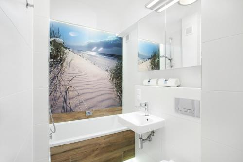 a bathroom with a sink and a picture of a beach at Sea Point Apartment - Hav Aparts in Gdańsk