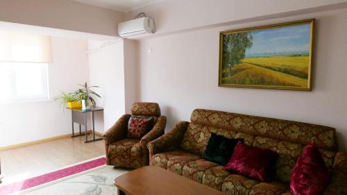 una sala de estar con sofá y una pintura en la pared en Bishkek Apartment Central, en Bishkek