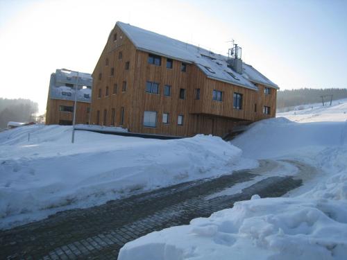 a building covered in snow next to a road at Apartmán u Kamila in Dolní Morava