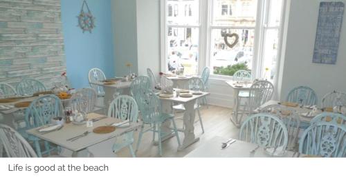 a dining room with tables and chairs and a window at Beachside Guest House in Llandudno