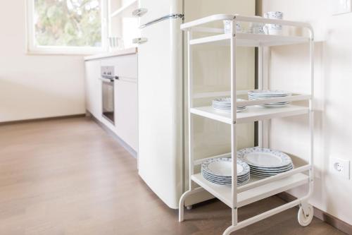a white shelf with plates on it in a kitchen at HOMEBOUND APARTMENTS Salzburg City II - contactless check-in in Salzburg