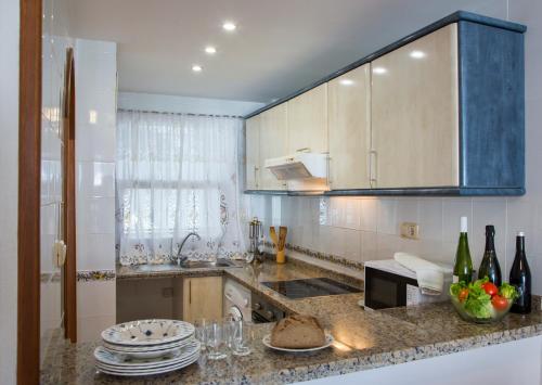 a kitchen with a sink and a counter with plates and wine bottles at Complejo Bellavista Residencial in Pego