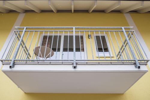 a balcony with a metal railing on a yellow wall at HOMEBOUND APARTMENTS Salzburg City II - contactless check-in in Salzburg