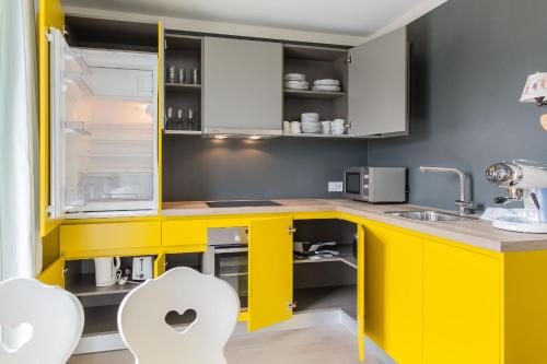 a yellow kitchen with white cabinets and white chairs at HOMEBOUND APARTMENTS Salzburg City II - contactless check-in in Salzburg