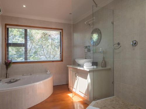 a bathroom with a tub and a sink and a window at Wilderness Gem Luxury Villa in Wilderness