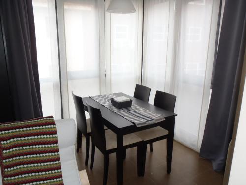 uma mesa preta e cadeiras num quarto com janelas em El Balconcito de San Millán III na Segóvia
