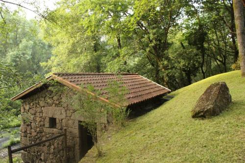 an old stone building on a grassy hill at Quinta do Rio Homem in Caldelas
